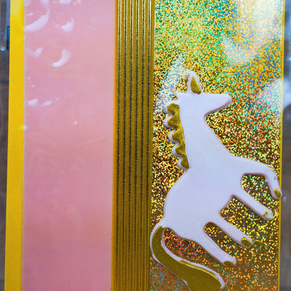 Nahaufnahme weißes Einhorn aus Wachs mit goldener Mähne auf Glitzer-Wachsplatte