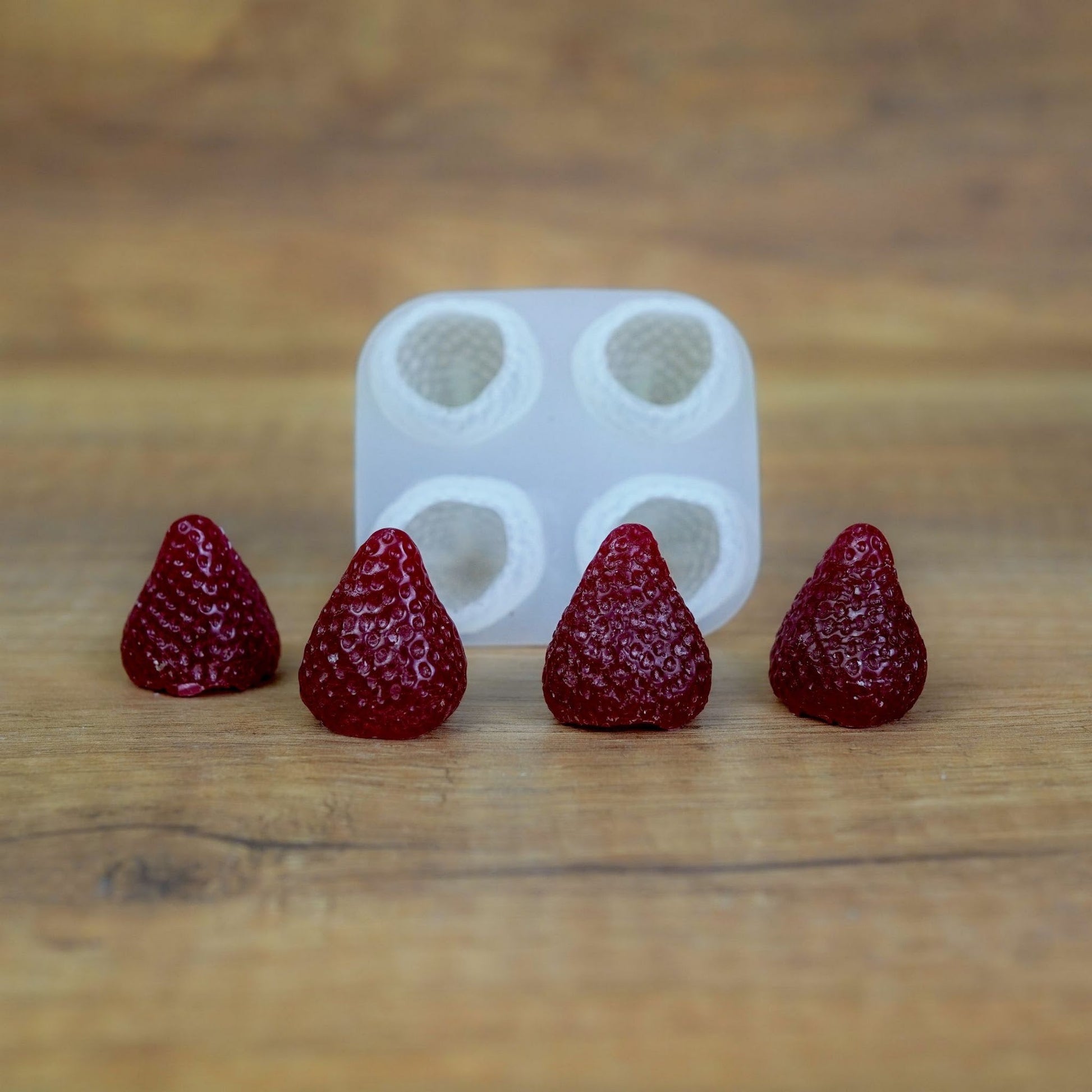 Silikonform mit 4 Beeren-Mulden und dunkelrot gegossenen Wachserdbeeren aus dem Set