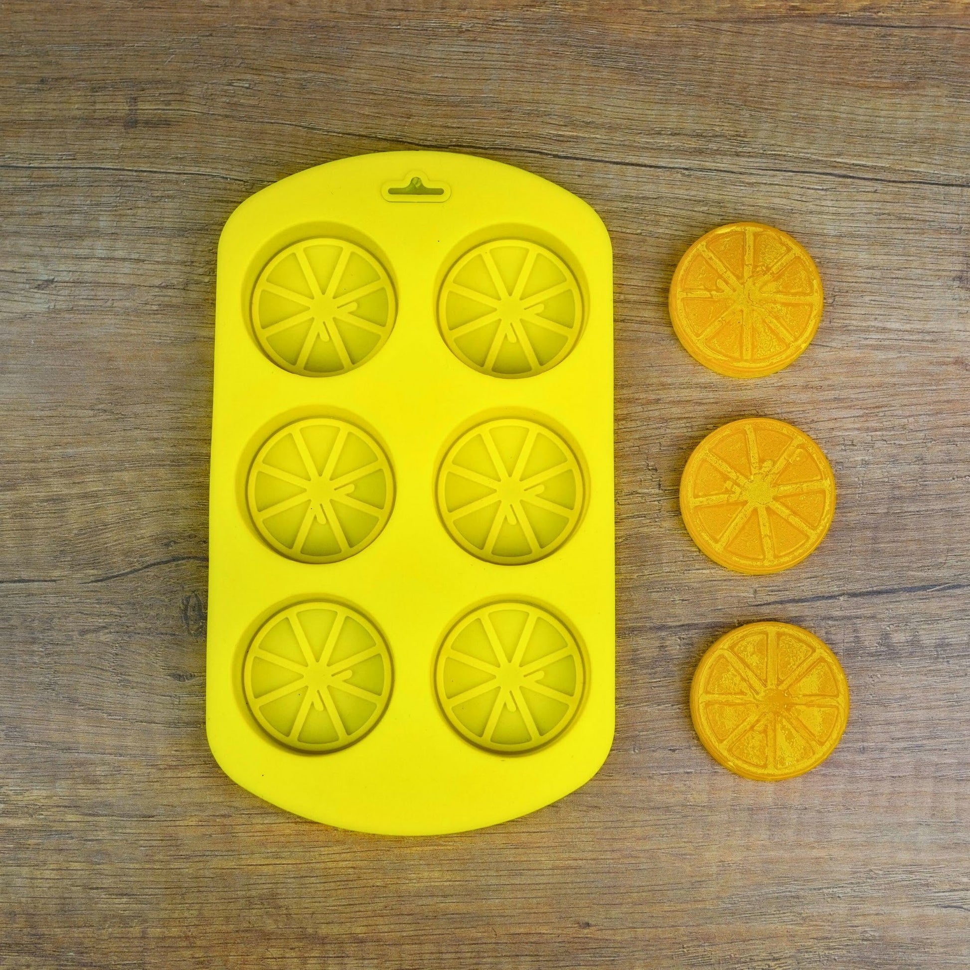 Silikonform mit 6 Zitrusscheiben und gegossenen orangen Fruchtscheiben aus dem Früchte-Set