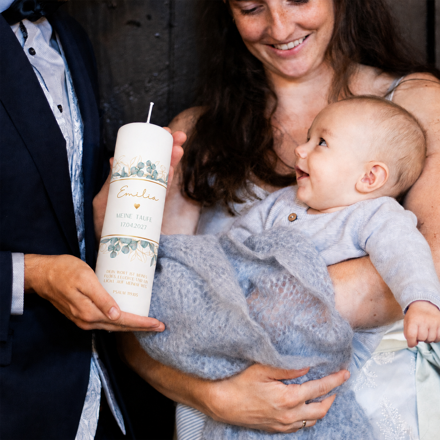Eltern halten Baby und die personalisierte Taufkerze Eukalyptus bei der Taufzeremonie
