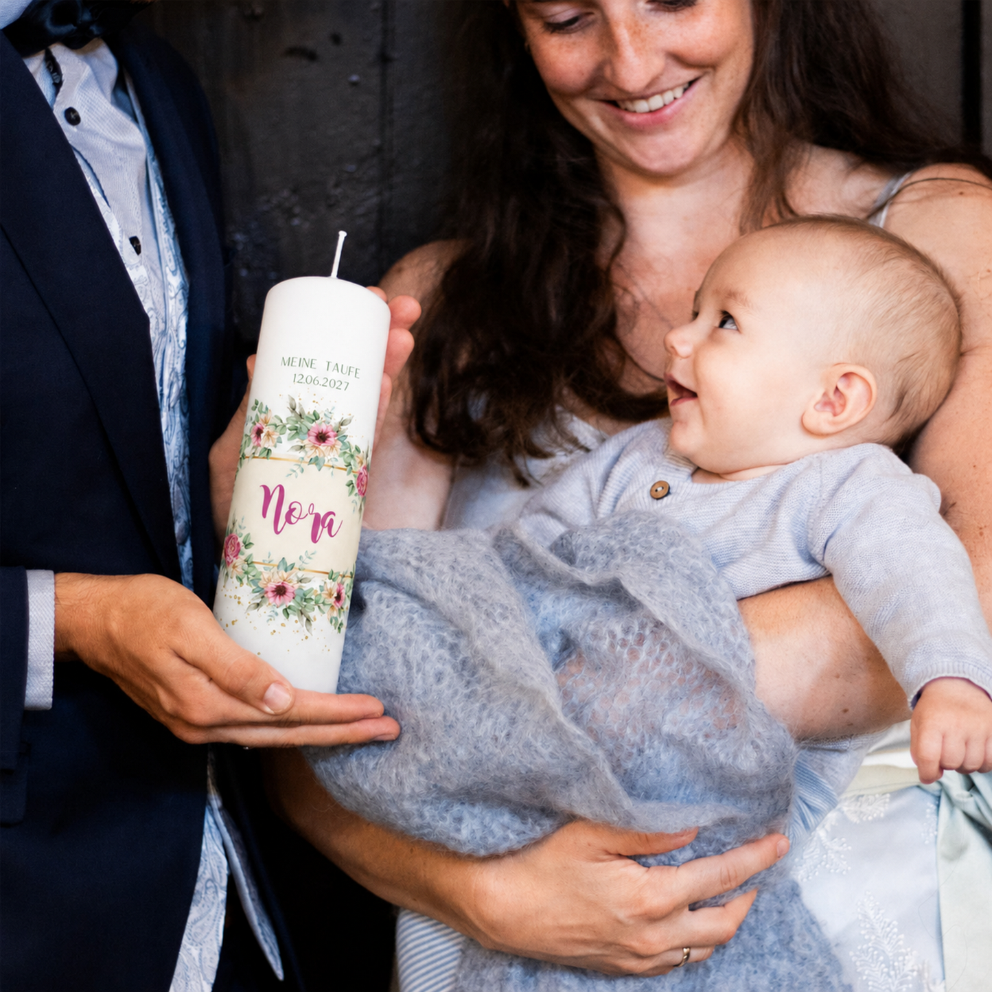 Eltern halten Baby und die personalisierte Taufkerze Rosengarten bei der Taufzeremonie