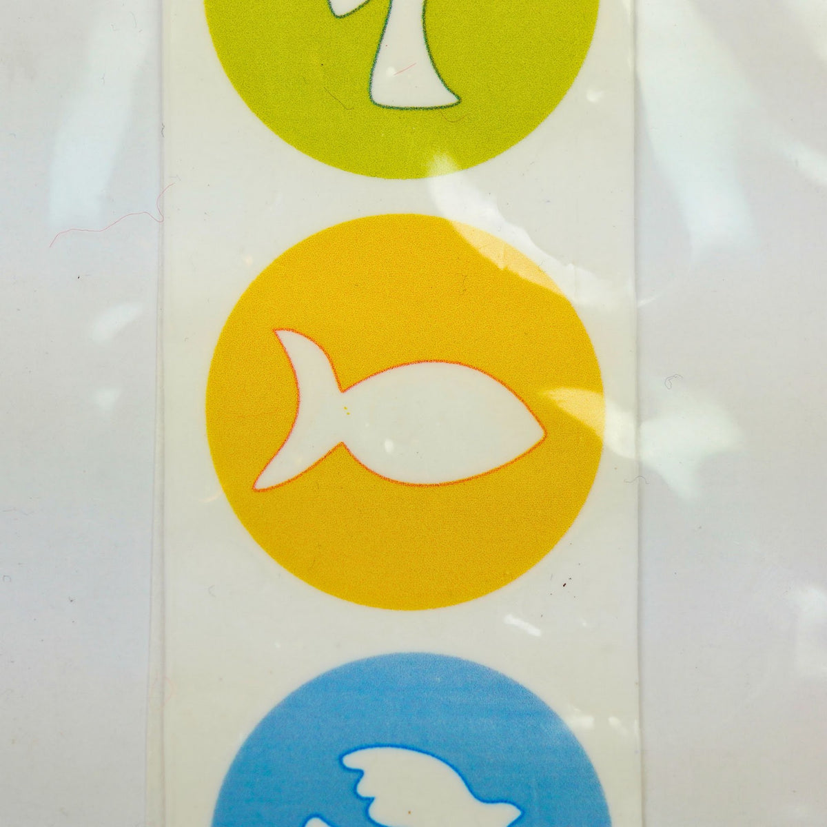 Nahaufnahme Wachsdekor Fisch auf gelbem Kreis zwischen Kreuz und Taube für Taufkerzen